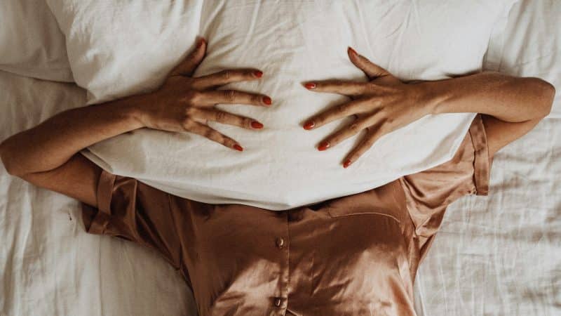 femme en pyjama sous un oreiller