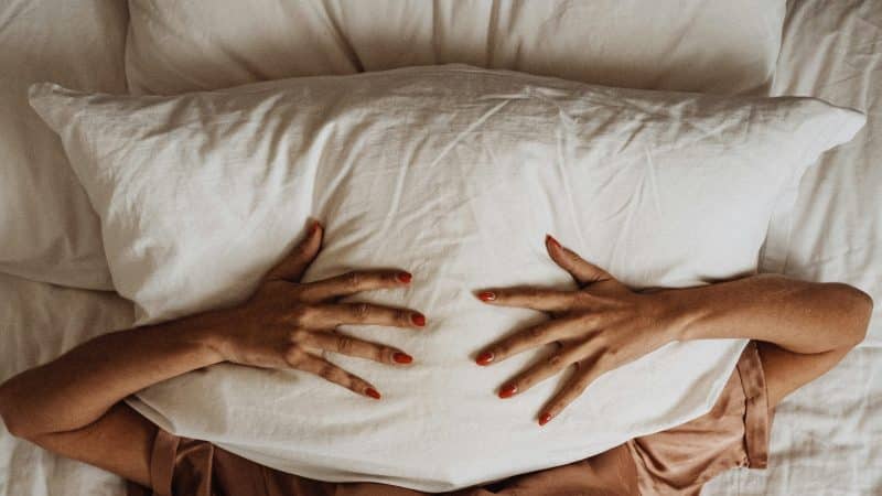 femme en pyjama sous un oreiller